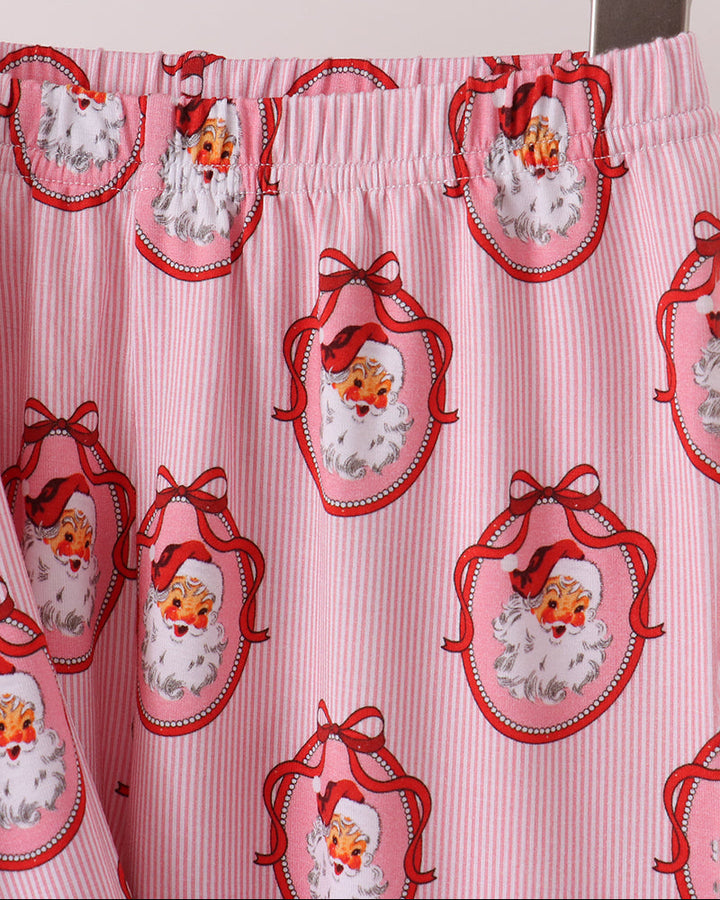 Pink pajama fabric with repeating Santa face icons and orange ruffle trim