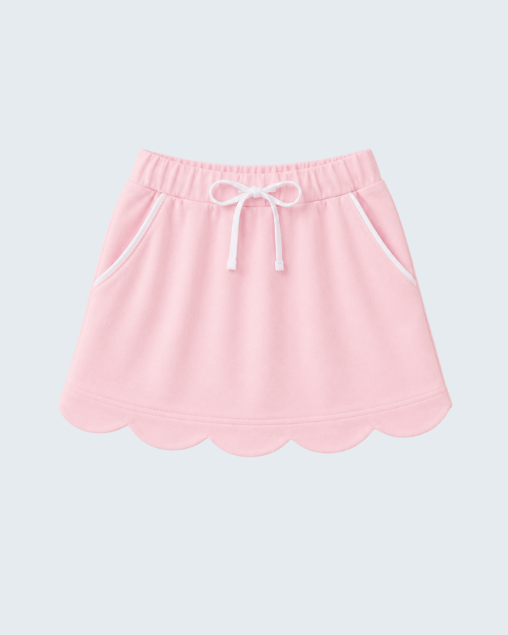 A light pink skort with a scalloped hem, white drawstring, and white piping details, shown against a light gray background.