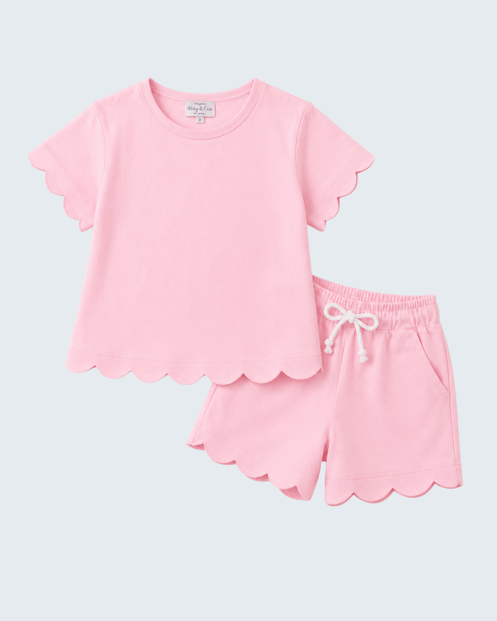 Pink short set with scalloped edges on a light gray background