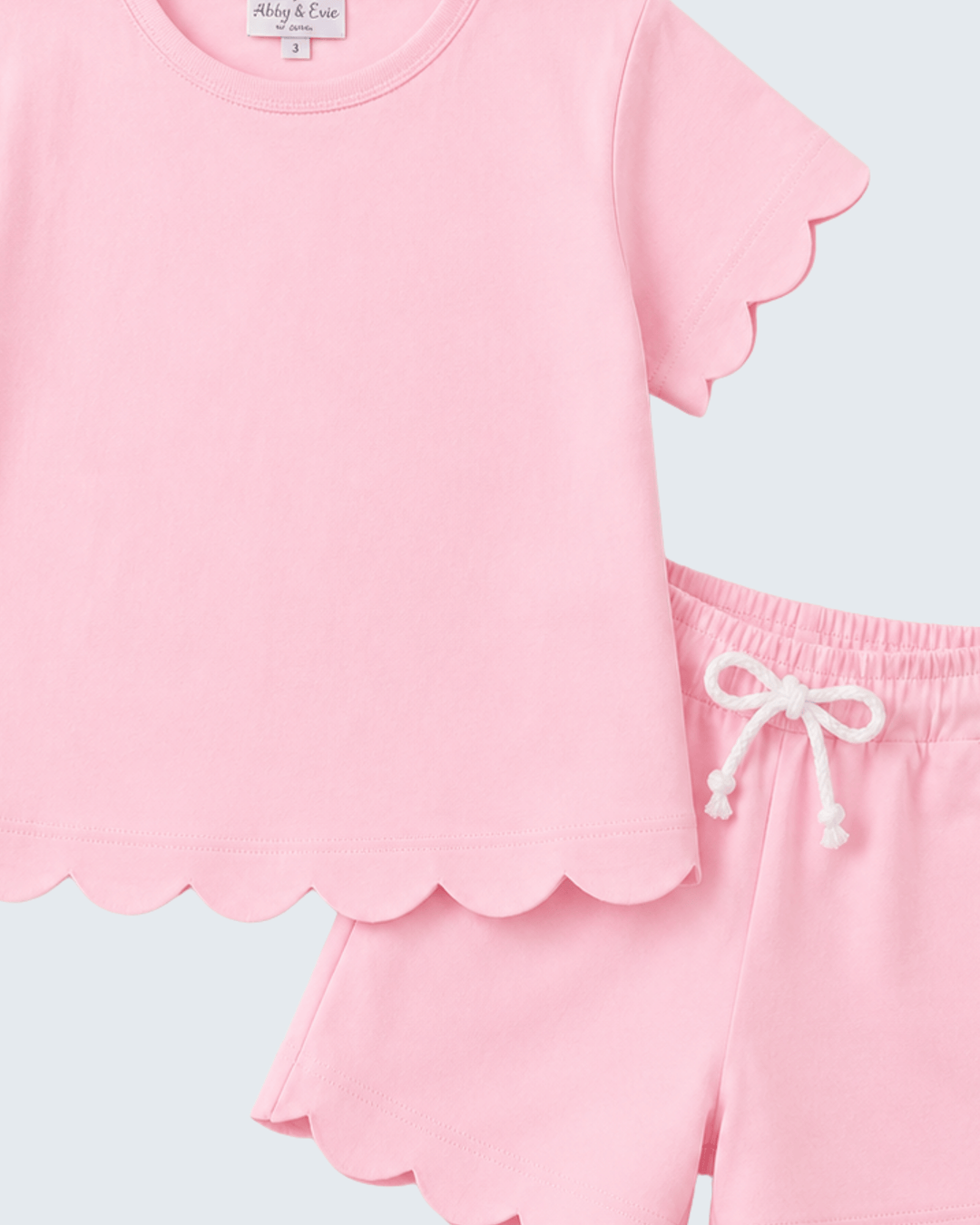 Pink shorts set with scalloped edges on a light blue background