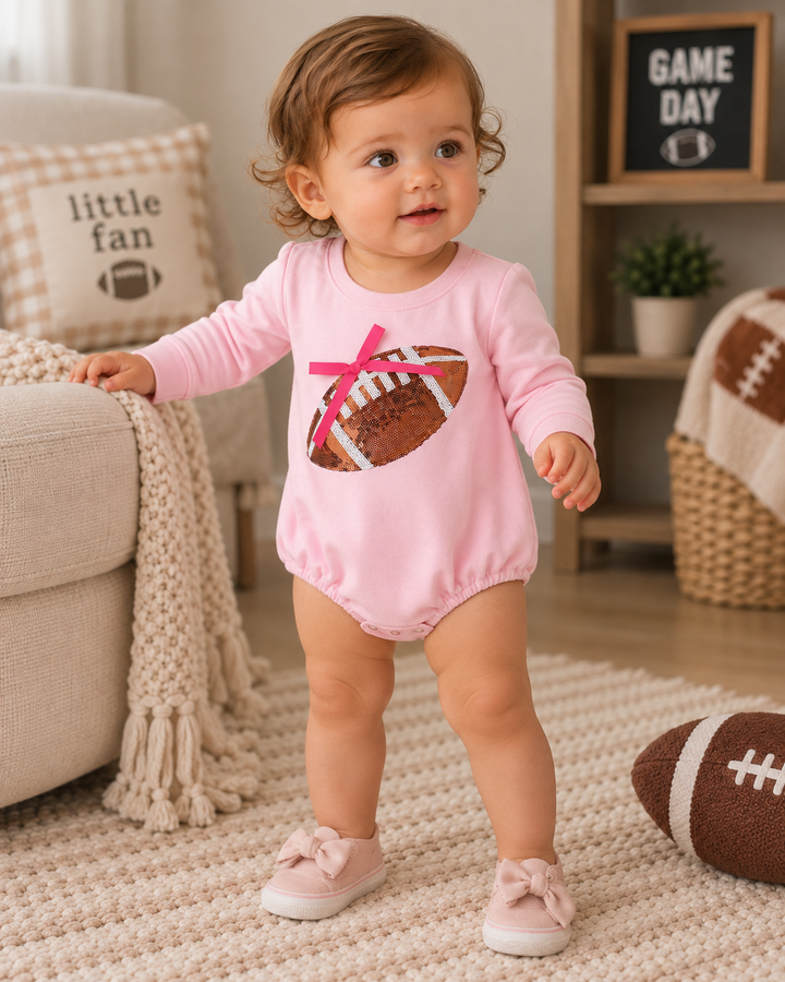 Pink long-sleeve bodysuit with sequin football patch and ribbon bow, snap bottom