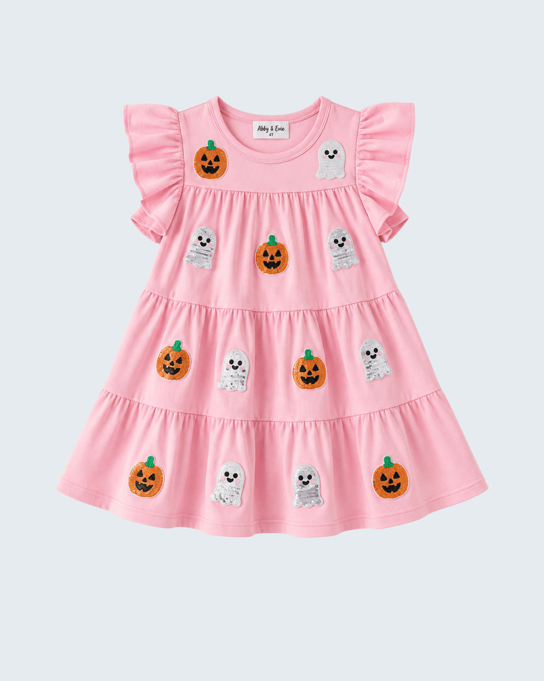 A pink tiered baby dress with ruffled sleeves, decorated with embroidered orange pumpkins and white ghosts, shown against a light gray background.