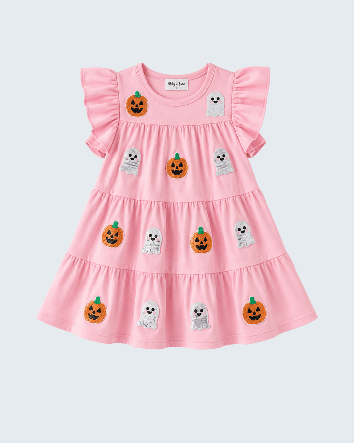 A pink tiered baby dress with ruffled sleeves, decorated with embroidered orange pumpkins and white ghosts, shown against a light gray background.
