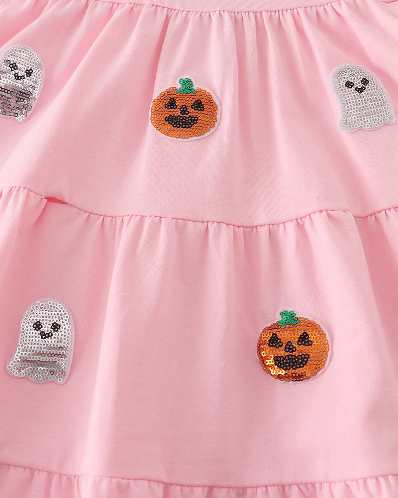 A close-up of a pink tiered dress featuring sequined pumpkin and ghost appliques.