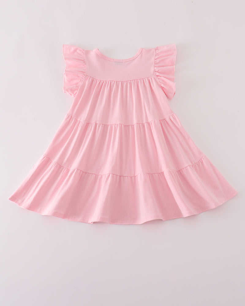 A light pink tiered baby dress with ruffled cap sleeves, laid flat against a light gray background.