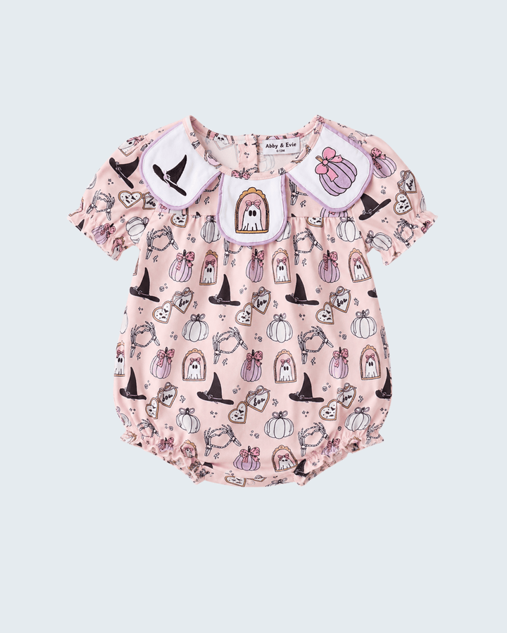 A baby romper in light pink with a Halloween-themed print of pumpkins, witch hats, ghosts, and a haunted house, featuring a white collar with embroidered details.