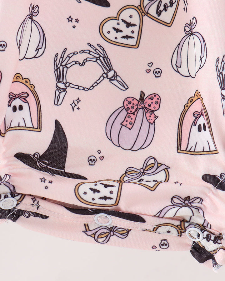 A close-up of a light pink fabric featuring a Halloween-themed print with pumpkins, ghosts, witch hats, skeleton hands, and candy corn.
