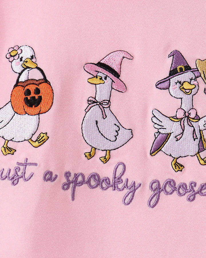 Pink shirt detail with embroidered geese and the text “just a spooky goose”