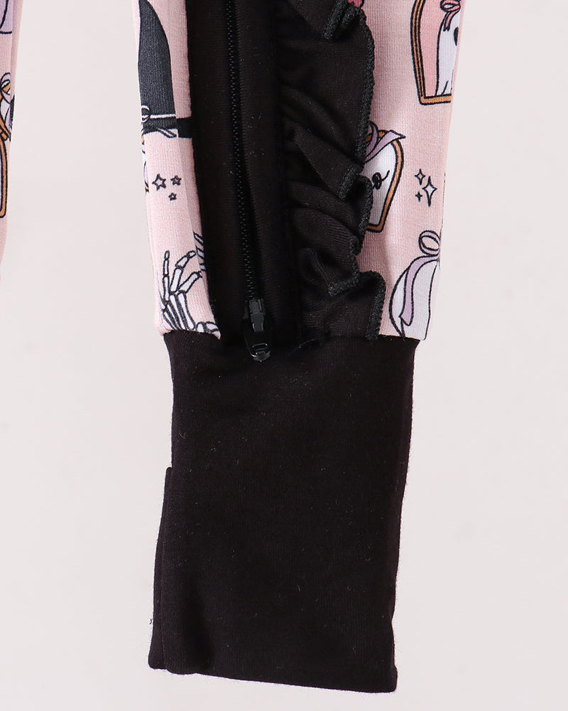 Close-up of a garment sleeve showing a light pink fabric with a black and white ghost pattern, a black ruffled trim, and a black elastic cuff.