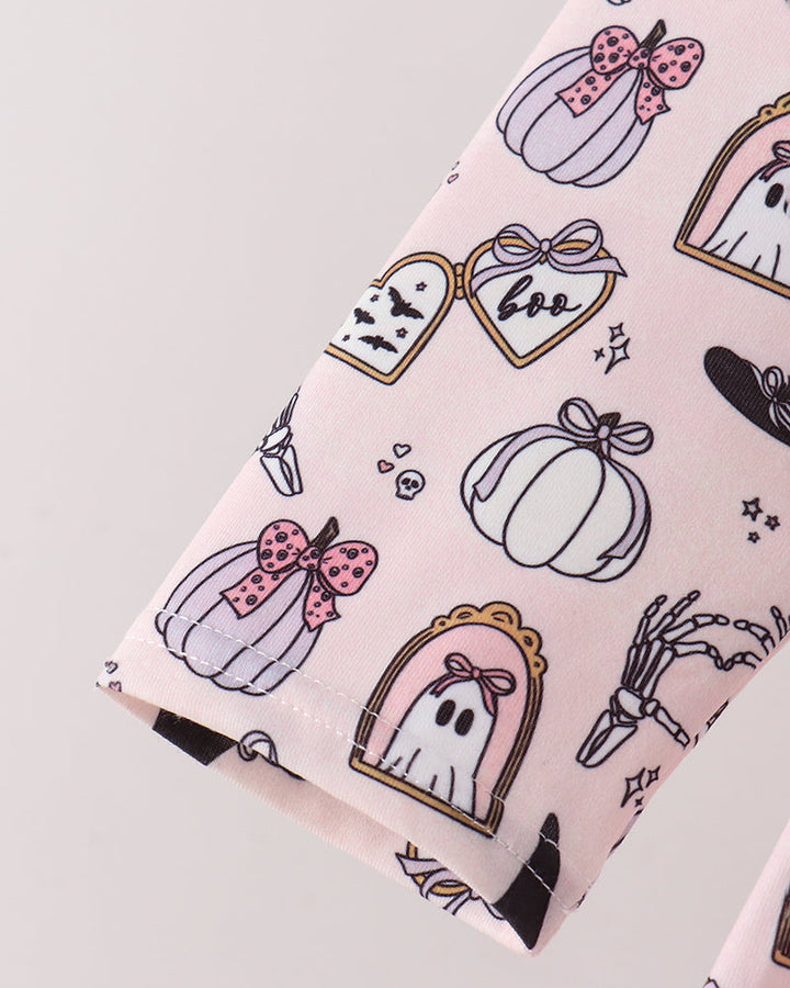 A close-up of a light pink fabric featuring a cute Halloween pattern with pumpkins, ghosts, skeletons, and hearts outlined in black and decorated with pink bows.