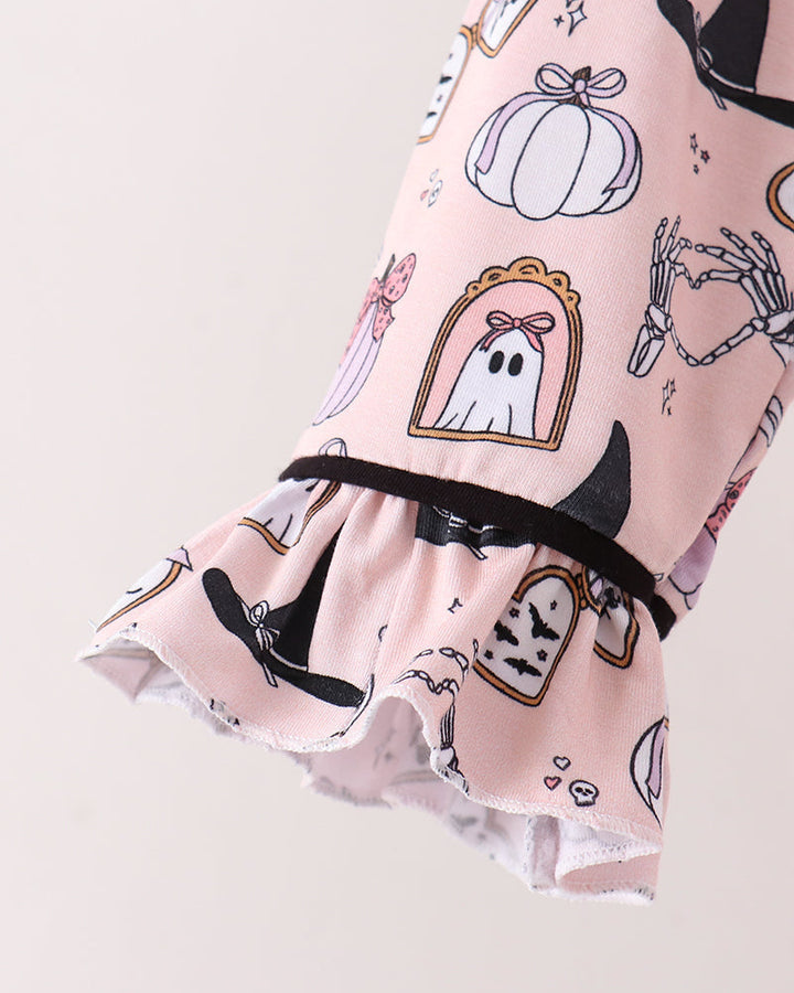 A close-up of a light pink ruffled sleeve or garment featuring a Halloween print with pumpkins, ghosts, witch hats, bats, and skeletons, finished with a black elastic band.