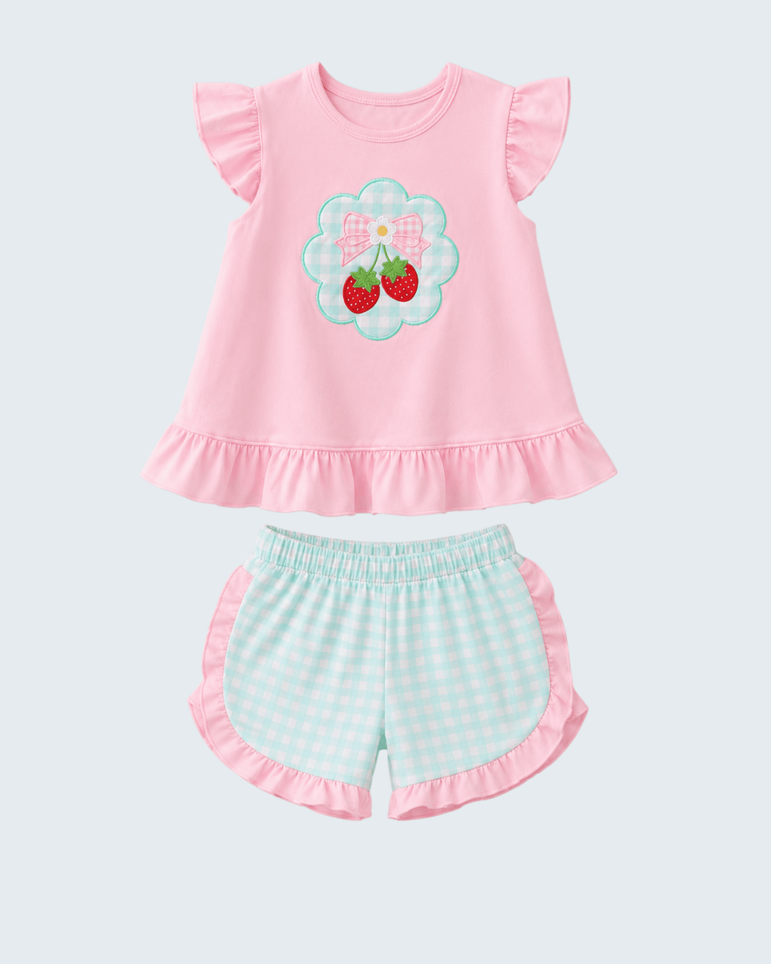 Pink top with floral design and green checkered shorts on a light gray background