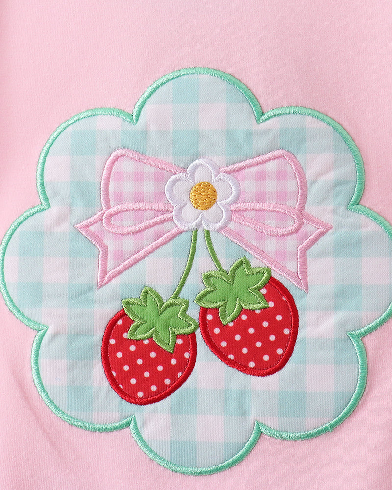 Pink garment with a floral design featuring strawberries and a bow.