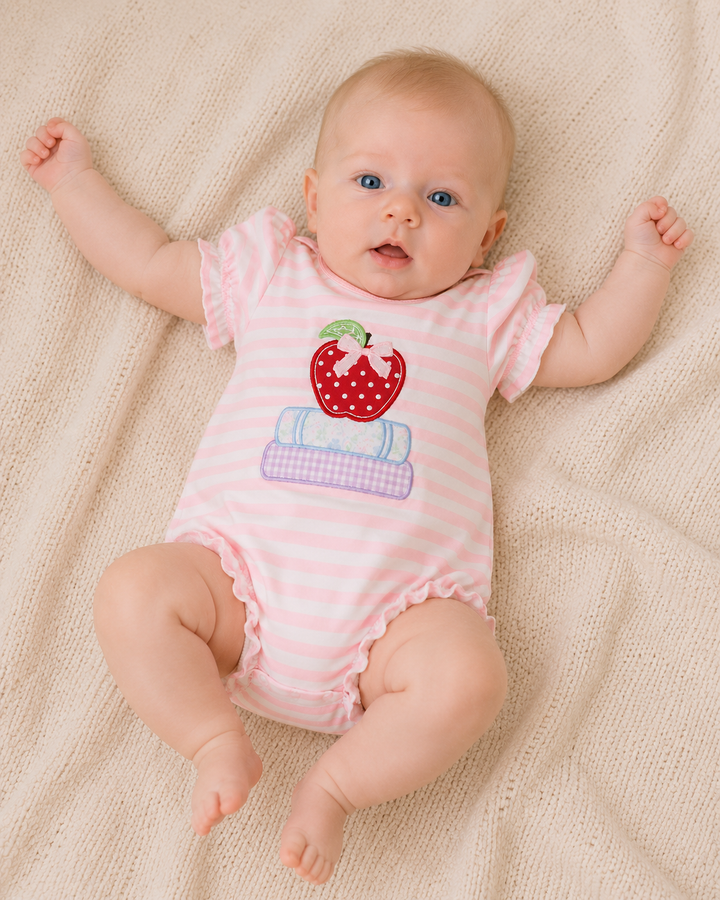 Baby girl in pink striped romper laying on a blanket