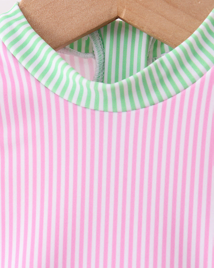 Pink and green striped garment on a wooden hanger with a white background