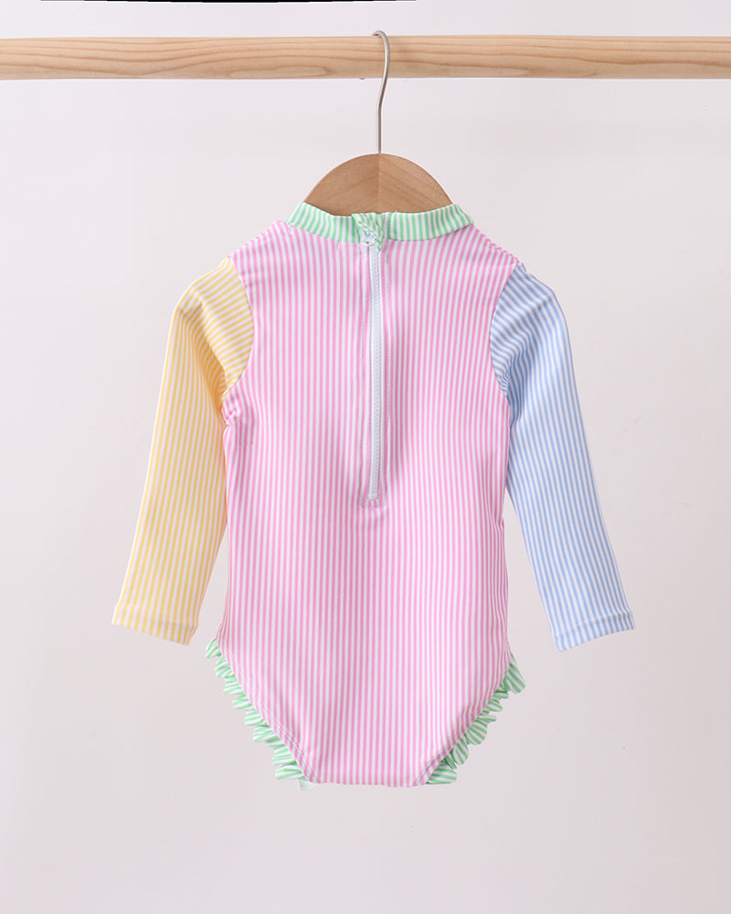 Colorful striped swimsuit on a hanger against a light background