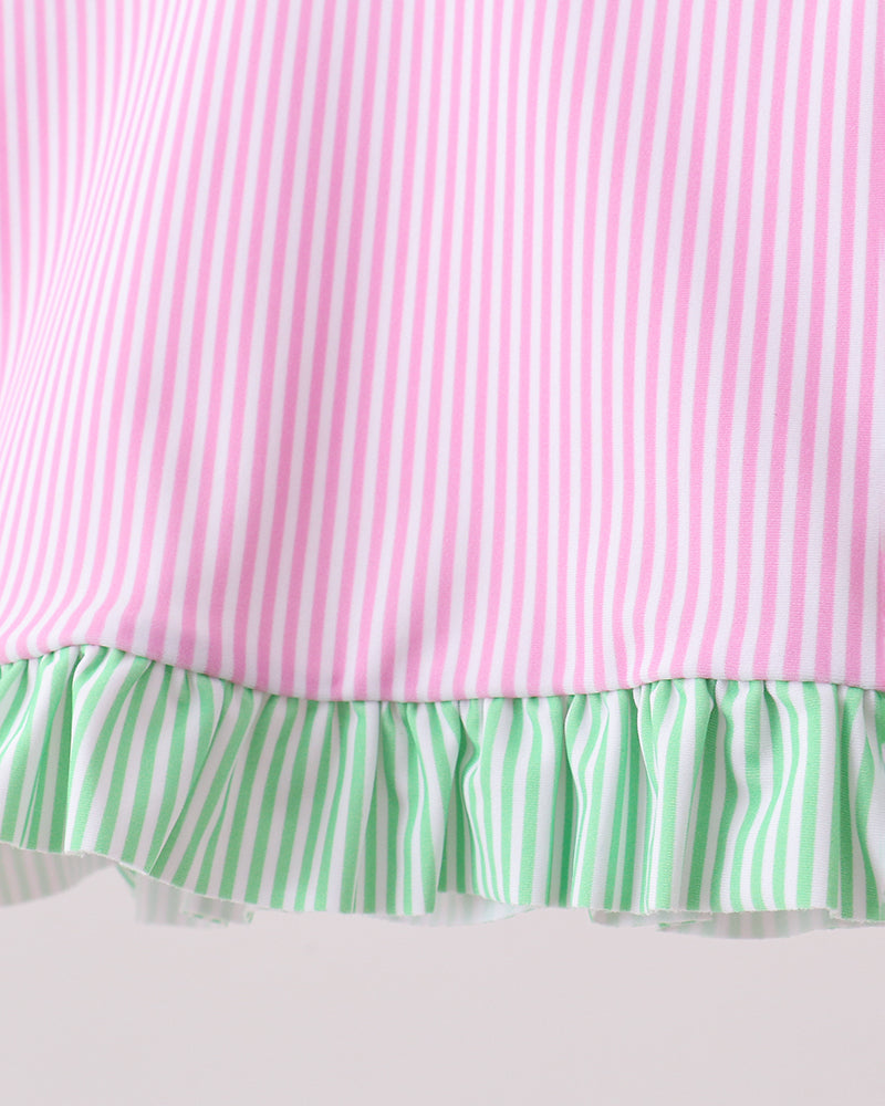 Close-up of a pink and green striped fabric with a ruffled edge on a white background
