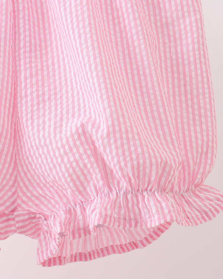 Close-up of a pink and white checkered fabric with ruffled edge on a light gray background