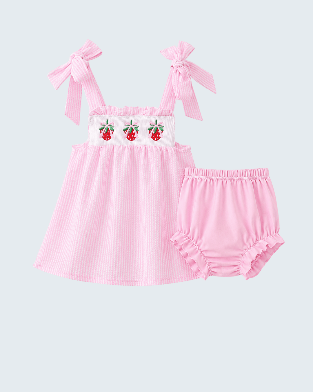 Pink baby dress with strawberry design and matching bloomers on a light gray background