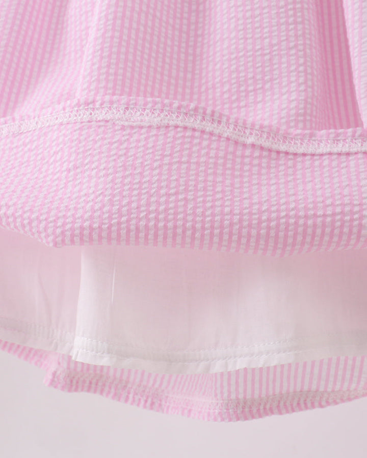 Close-up of a pink textured fabric with white trim on a light pink background
