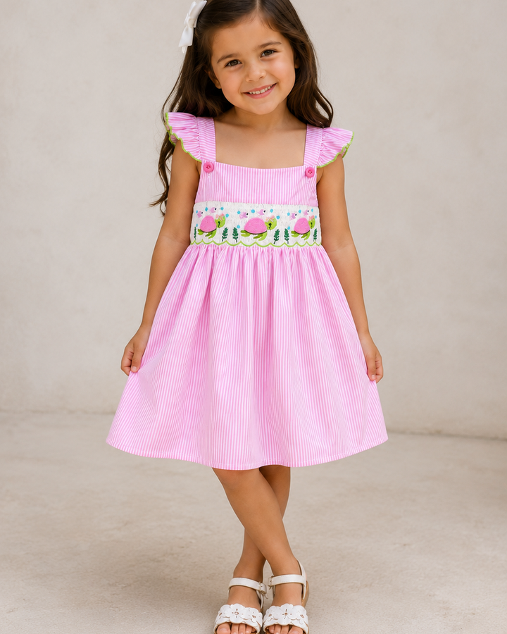 Young girl wearing a pink dress with floral embroidery on a beige background
