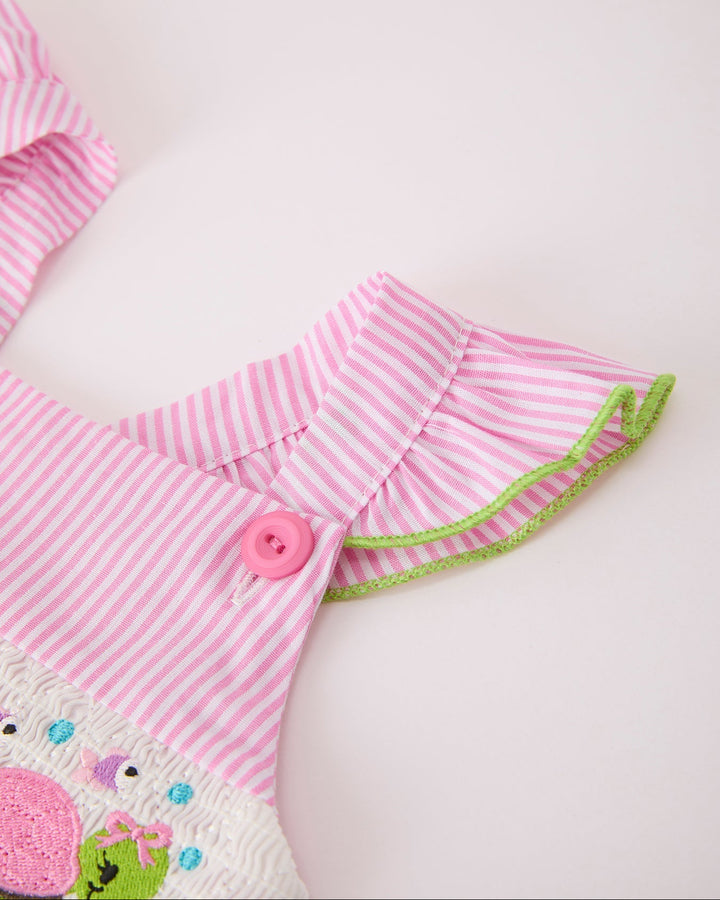 Pink and white striped outfit with a button and green trim on a light pink background