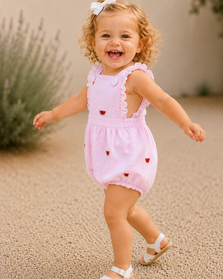 Child in a pink romper with heart patterns outdoors