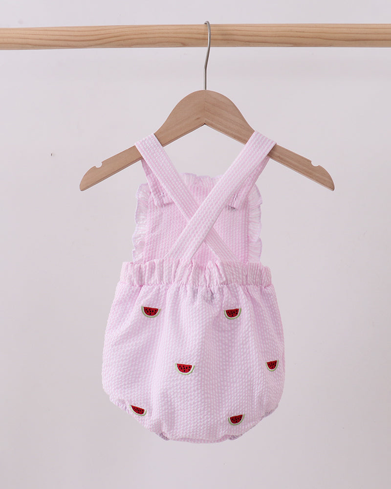 Pink baby romper with red accents on a wooden hanger against a white background