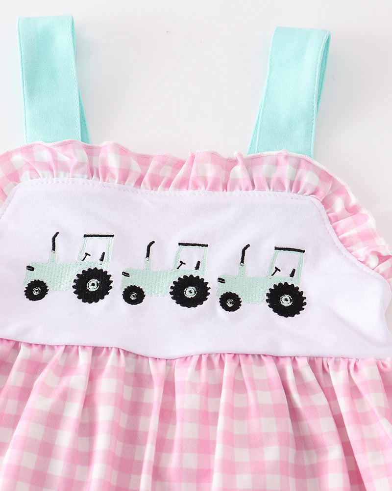 Pink checkered dress with green straps and tractor design on a white background
