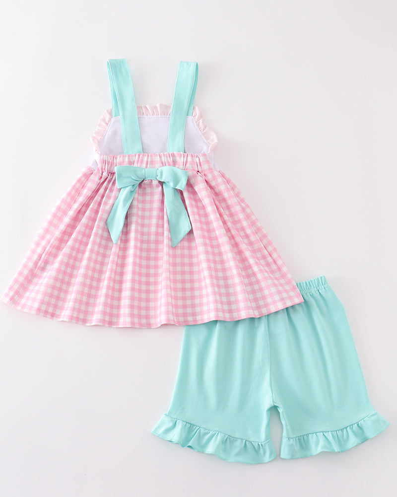 Pink checkered dress with suspenders and light blue shorts on a white background
