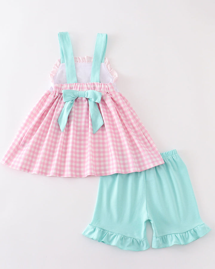 Pink checkered dress with suspenders and light blue shorts on a white background
