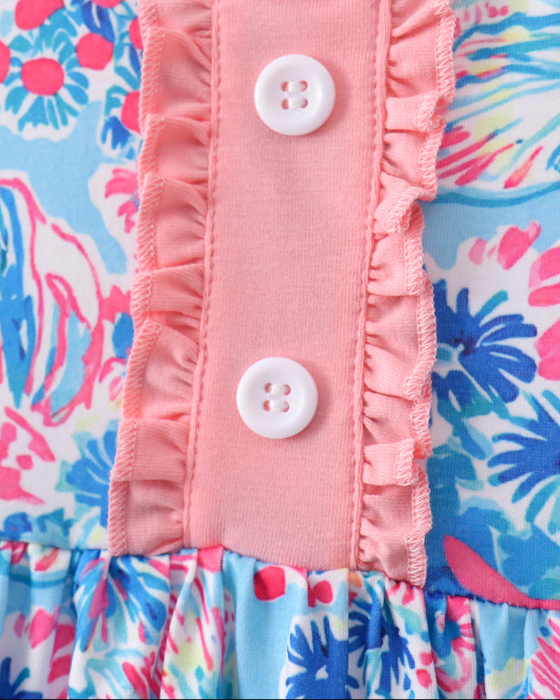 Close-up of a pink ruffled fabric with buttons on a colorful floral background