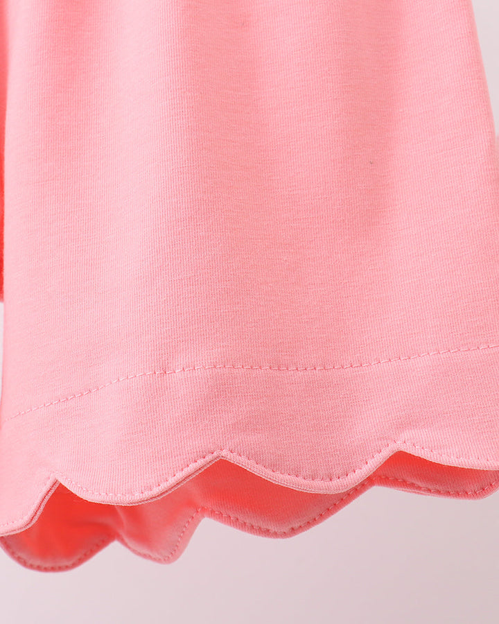 Close-up of a pink fabric with scalloped edge on a light gray background