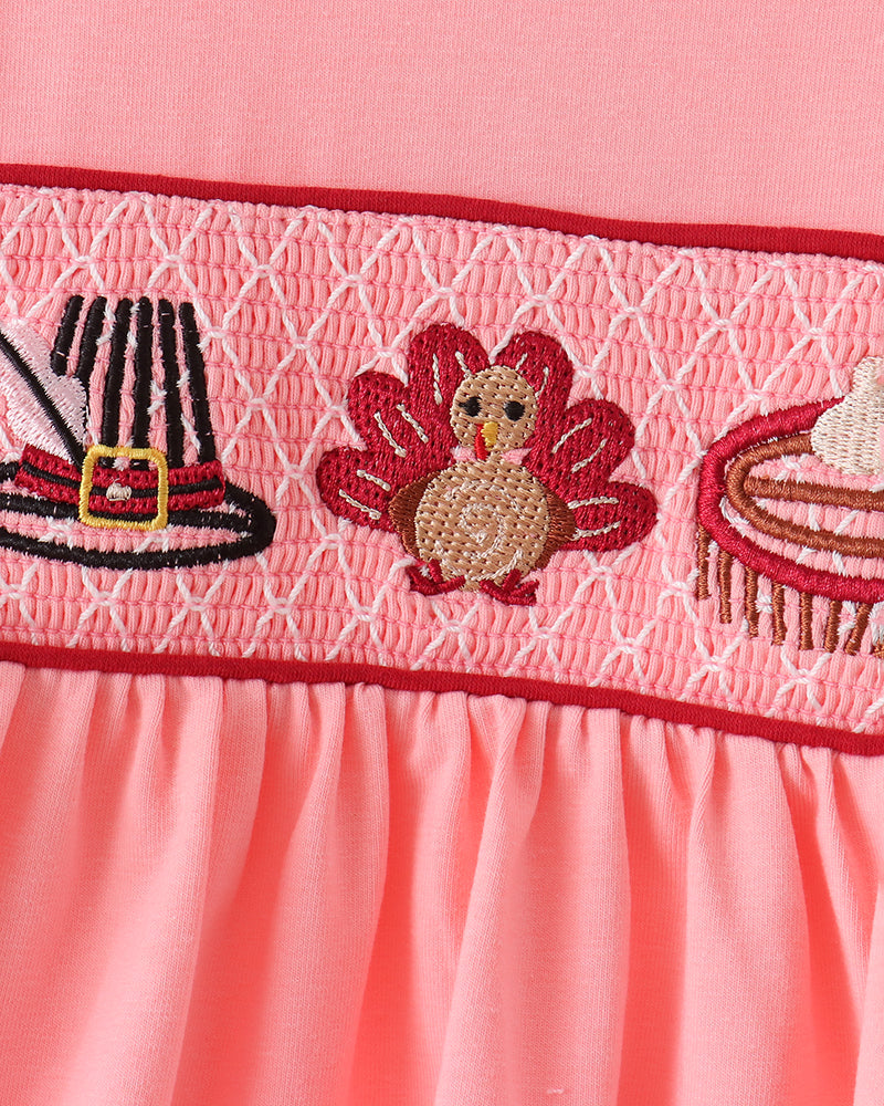 Pink dress top close-up: smocked band with turkey and ribbon embroidery
