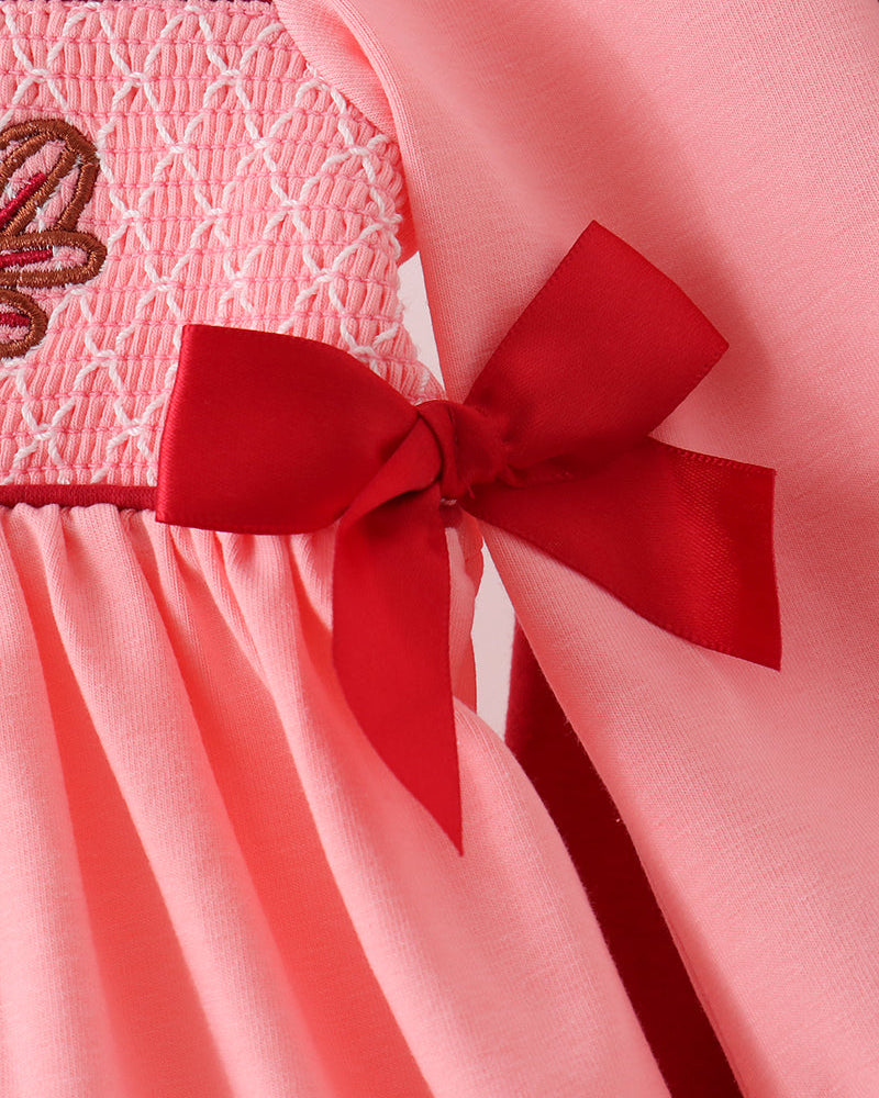 Pink dress top sleeve with large red bow on embroidered smocked panel
