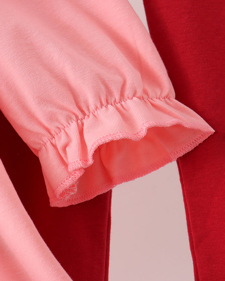Pink sleeve hem with ruffled cuff over red leggings