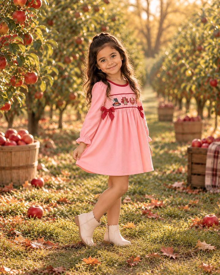 Pink long-sleeve dress with embroidered turkey panel and red bow accents, knee length