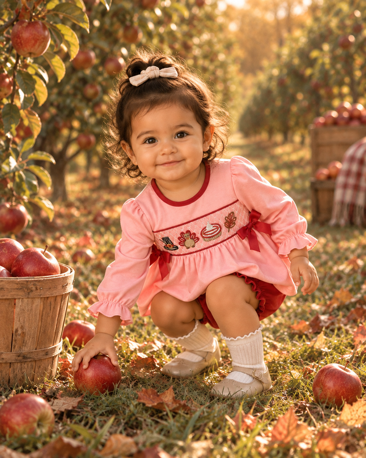 Toddler in pink smocked bow top with turkey print and matching red bloomers, long sleeves