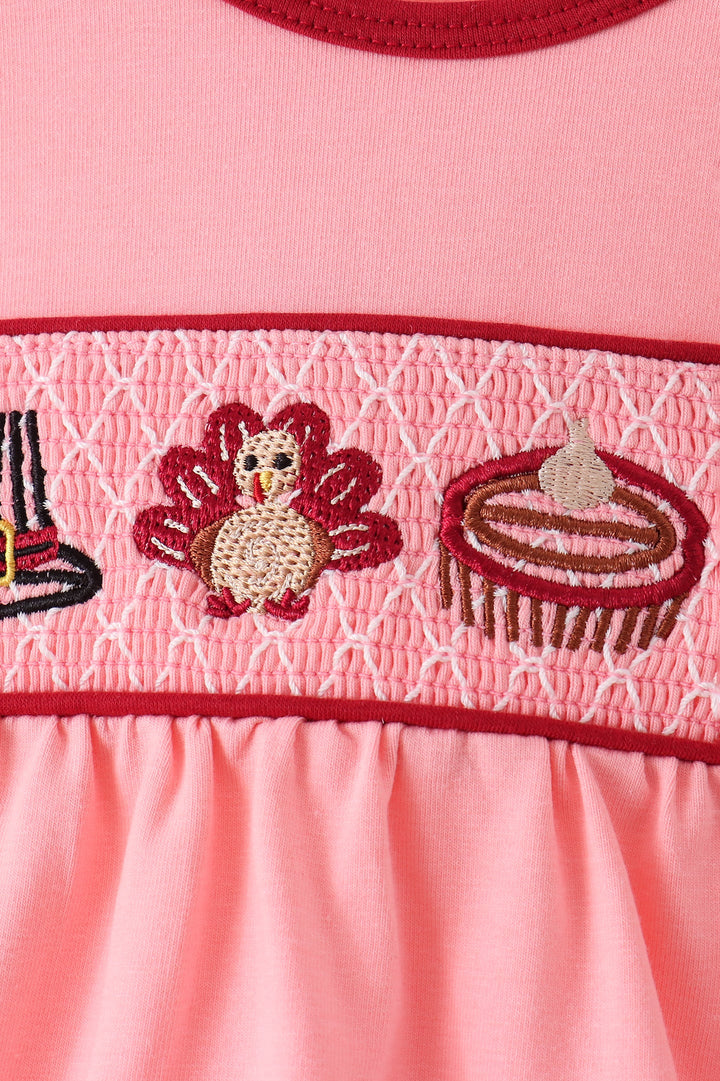 Pink smocked band with turkey and dessert motifs on baby bubble romper