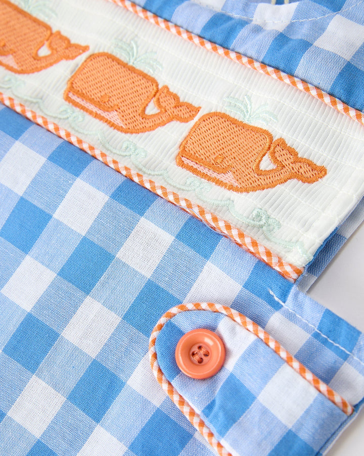 Close-up of a blue checkered fabric with orange accents and a button.