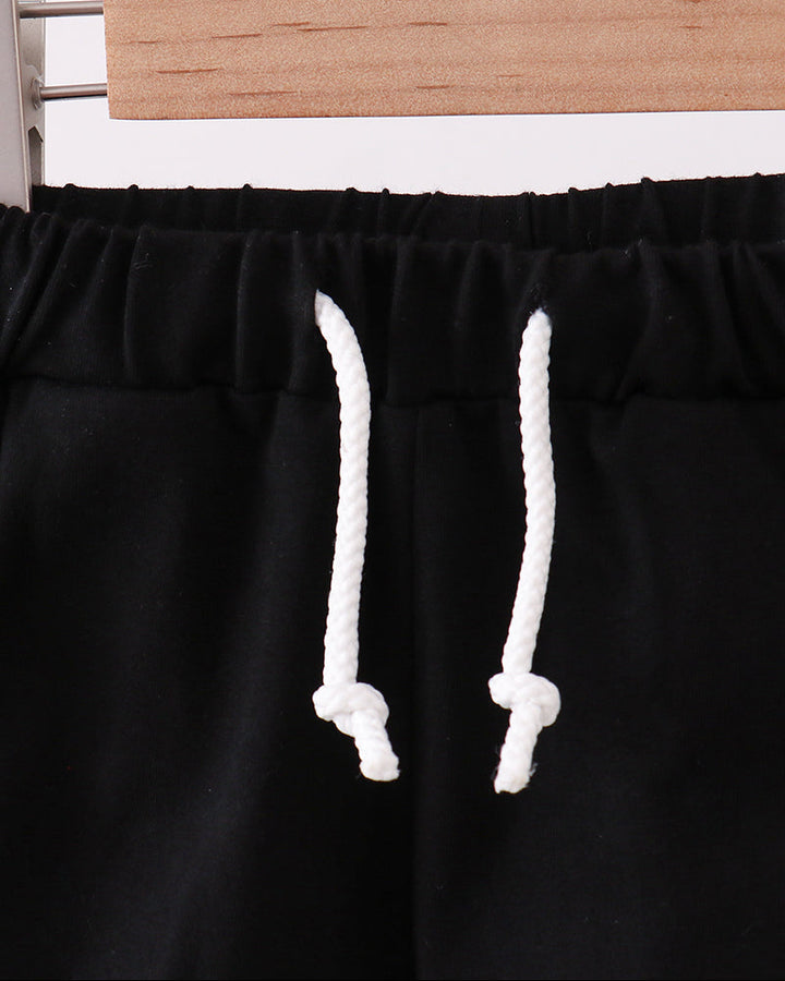 Black drawstring shorts with elastic waistband and white rope ties, close-up