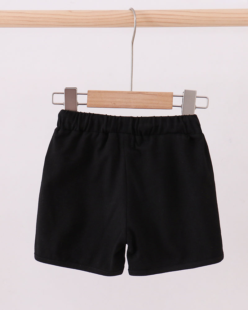 Black drawstring shorts with elastic waist, hanging on wooden hanger
