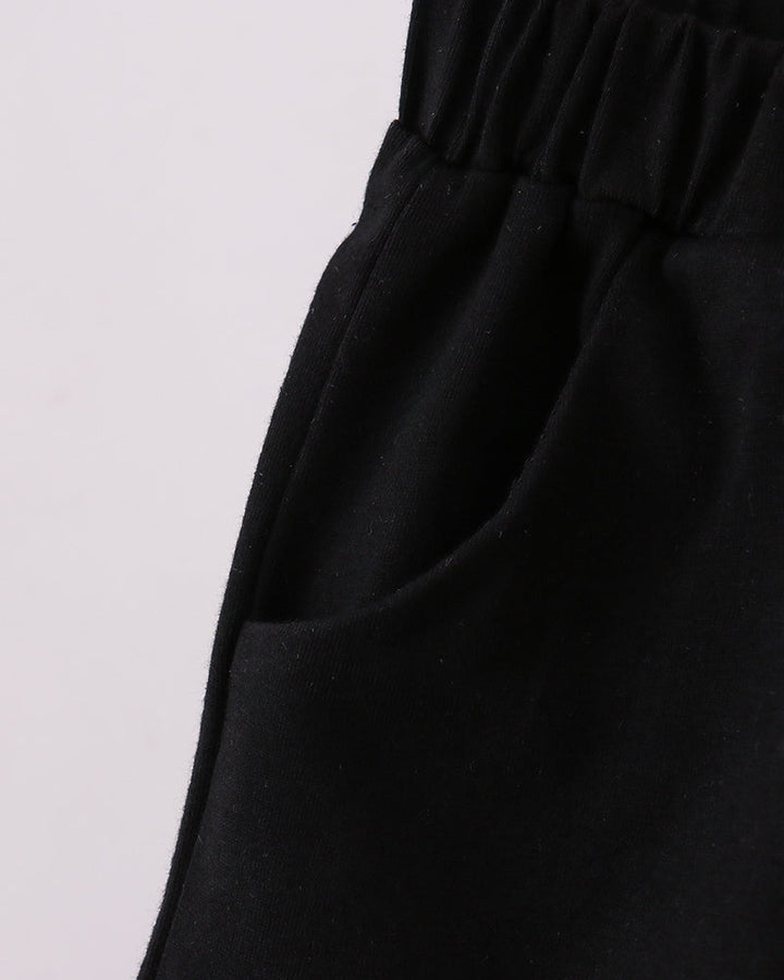 Black shorts with elastic waistband and draped fabric, side view