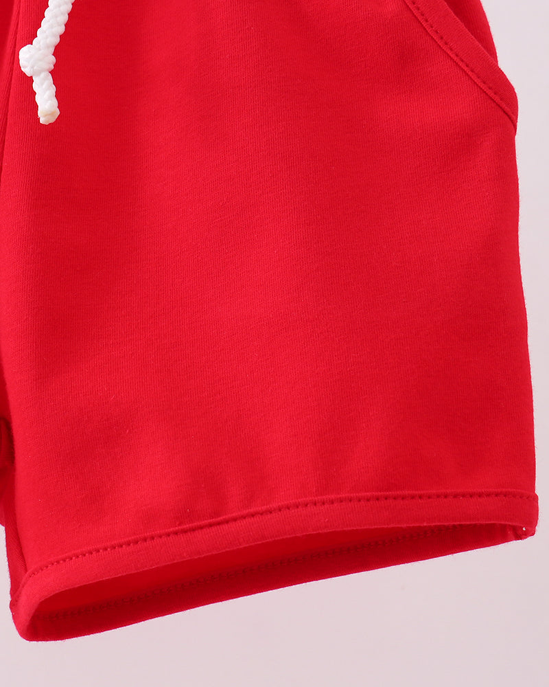 Red shorts with elastic waistband and white drawstring cords, close-up side