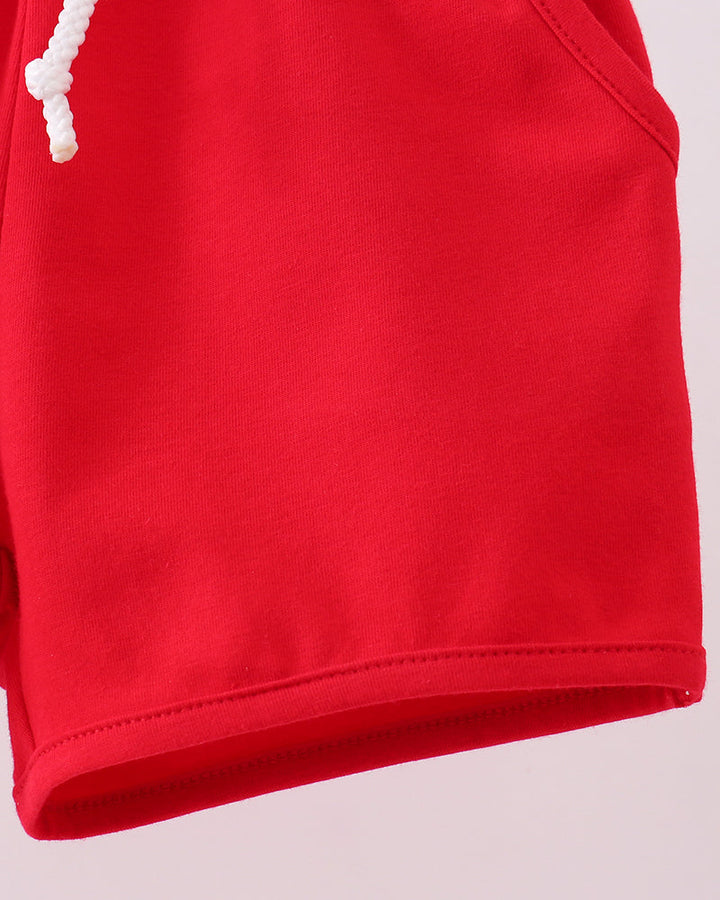 Red shorts with elastic waistband and white drawstring cords, close-up side