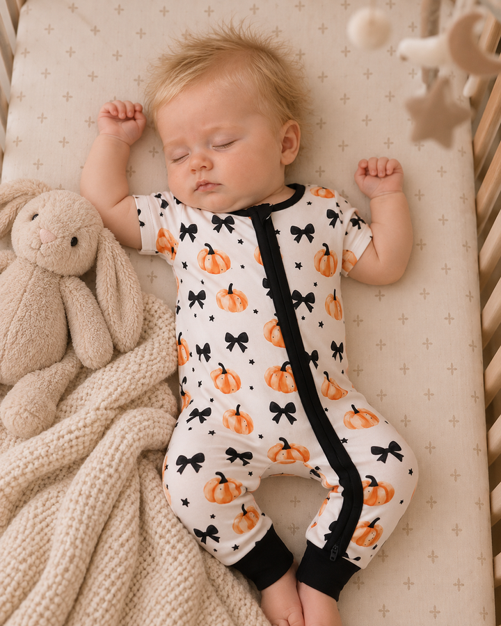 Bamboo zip romper with pumpkin and bow print, black trim, baby wearing it