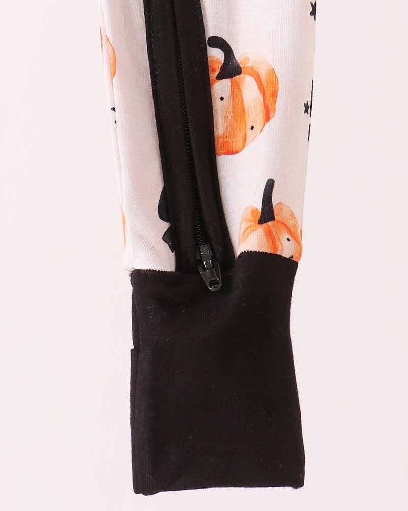 Black-cuffed romper with front zipper; white fabric with orange pumpkin and black bow print
