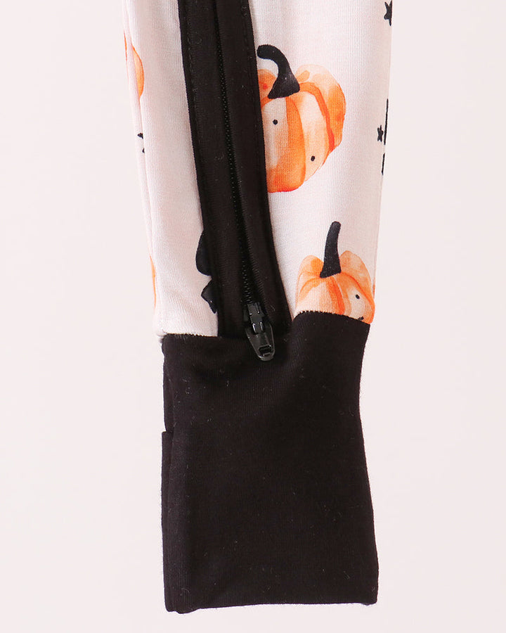 Black-cuffed romper with front zipper; white fabric with orange pumpkin and black bow print