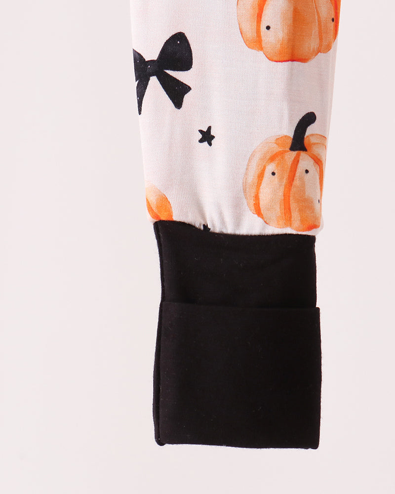 White romper with orange pumpkin pattern and solid black lower pocket panel