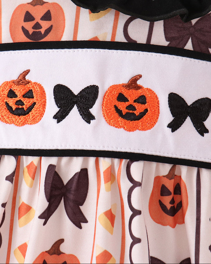 White romper with black ruffle trim and orange pumpkin applique stripe across the chest